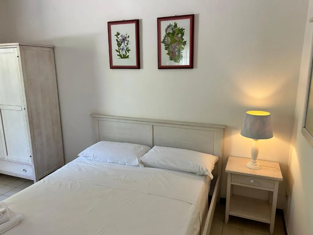 Camera da letto luminosa con letto matrimoniale, armadio bianco e lampada