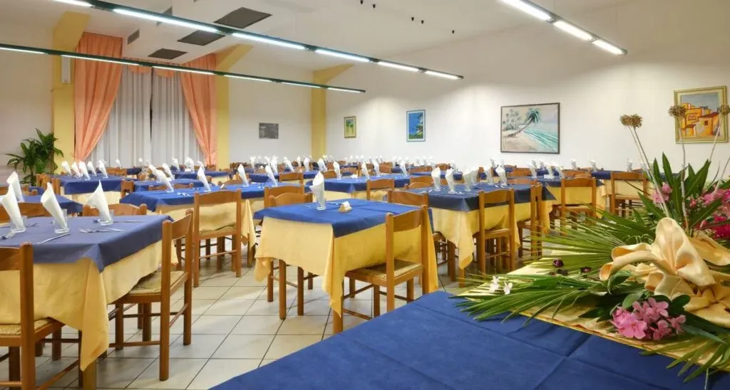 Ampia sala da pranzo con tavoli apparecchiati e decorazioni floreali