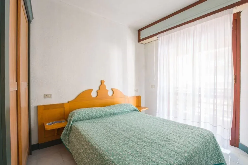 Camera da letto matrimoniale con copriletto verde e ampia finestra