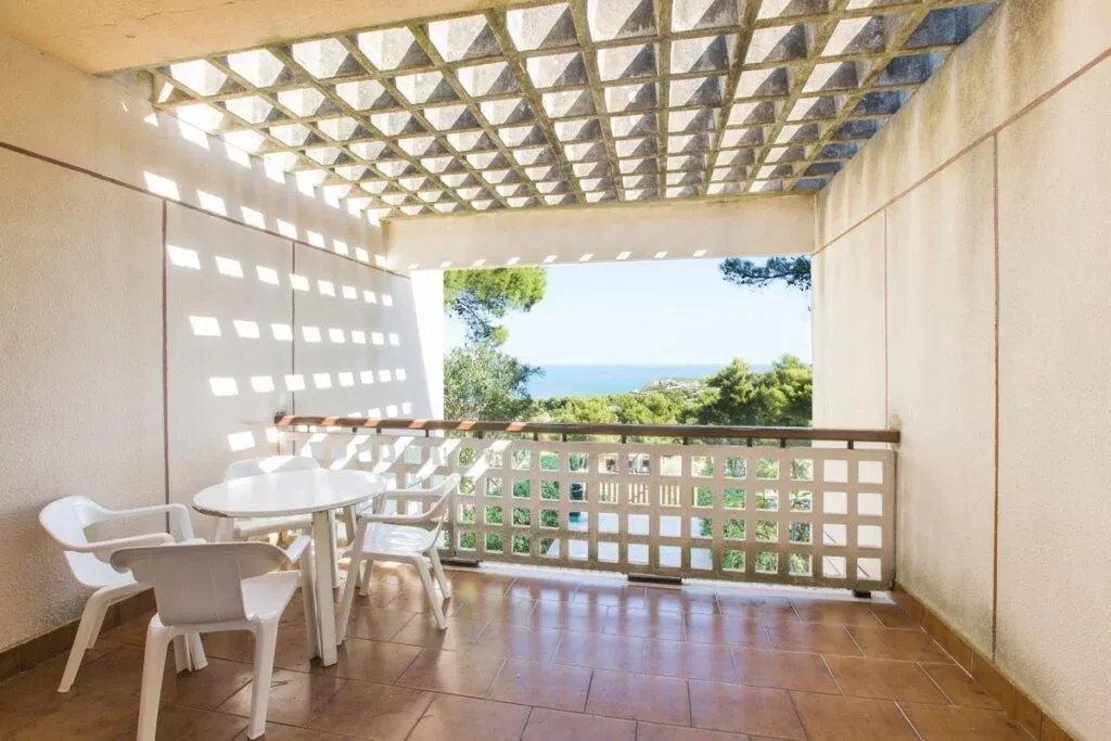 Terrazza coperta con tavolo e sedie e vista sul mare e la pineta