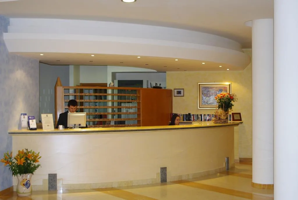 Reception dell'hotel con bancone curvo e personale al lavoro