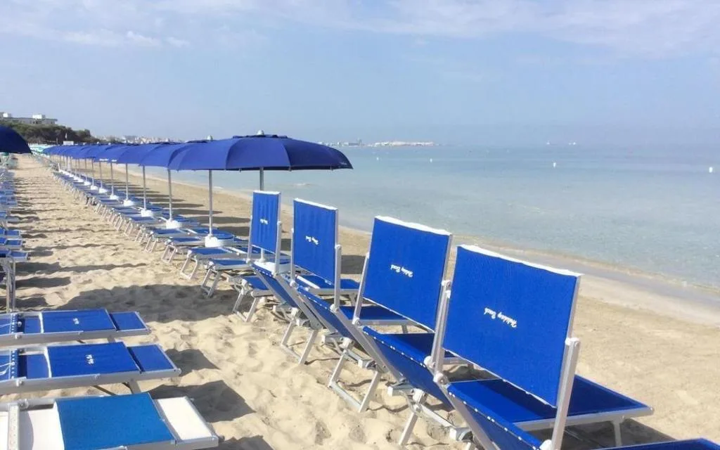 Spiaggia sabbiosa con lettini e ombrelloni blu in riva al mare