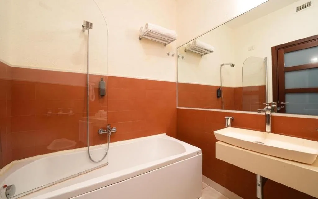 Bagno con vasca, doccia, lavabo e pareti piastrellate arancioni