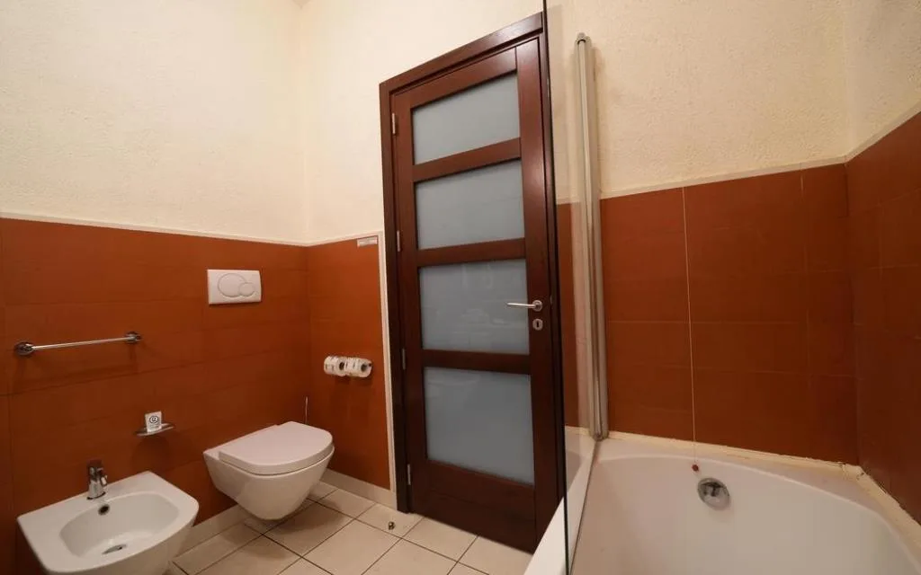 Bagno con vasca, wc, bidet e porta in legno con vetro