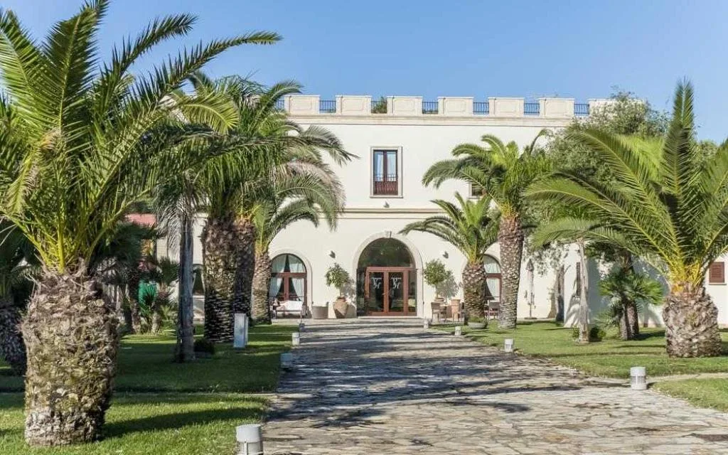 Facciata elegante della villa principale con palme e vialetto d'ingresso