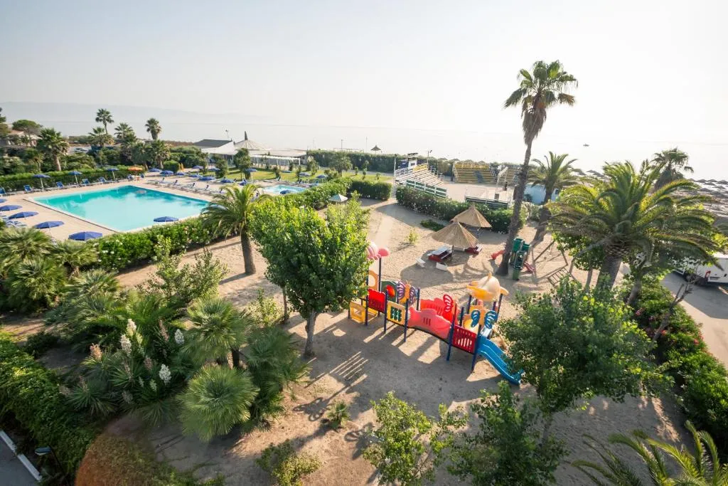 Area giochi per bambini con piscina e mare sullo sfondo tra le palme