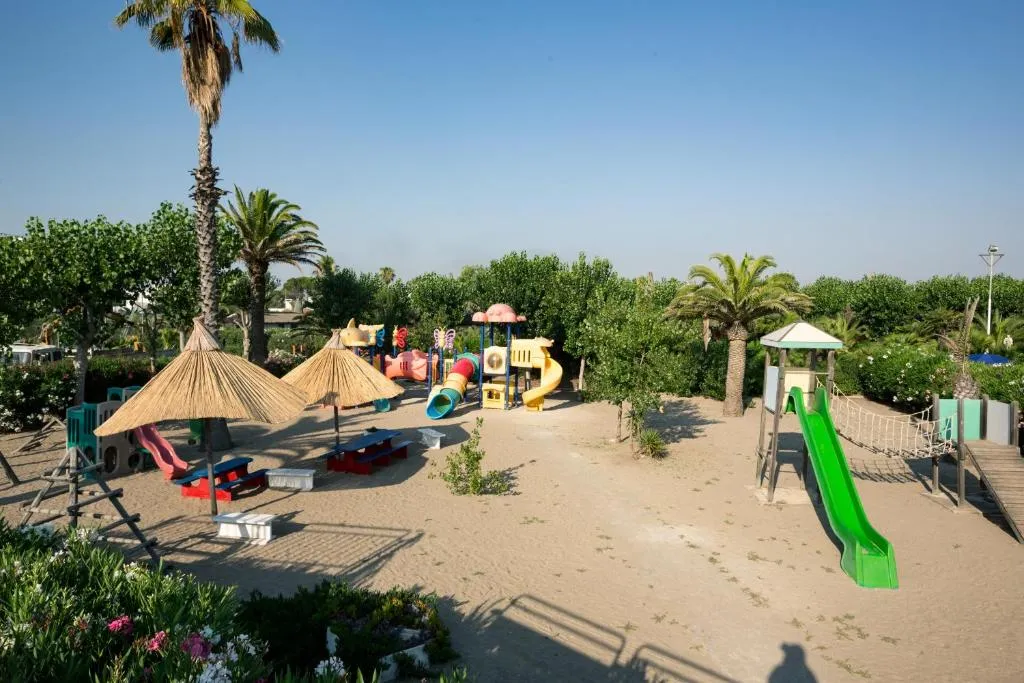 Parco giochi per bambini con scivoli sulla sabbia tra le palme