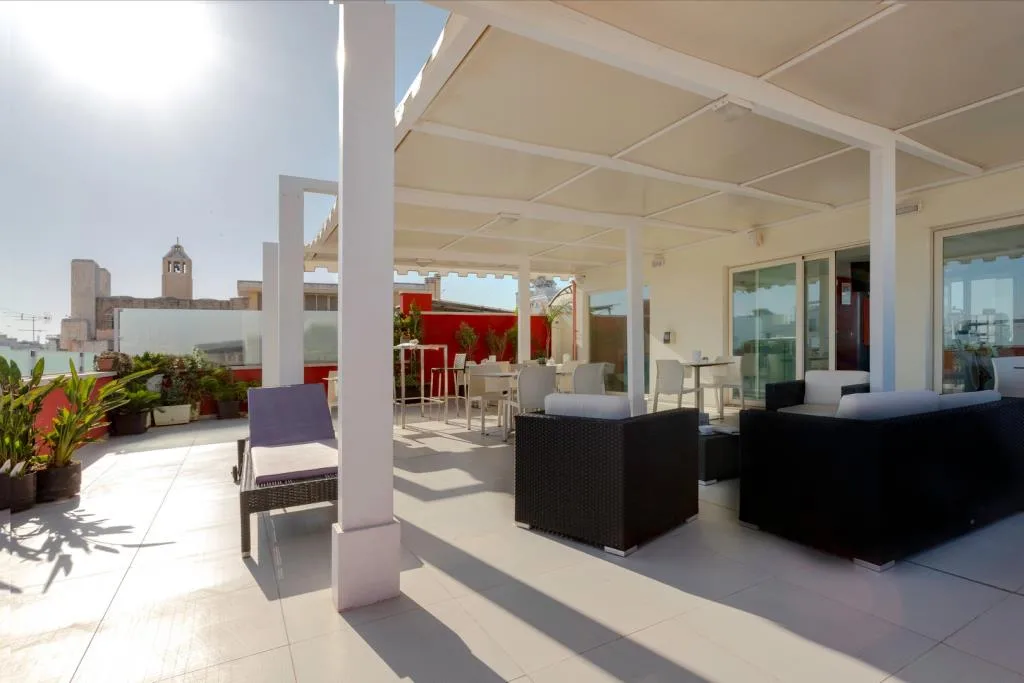 Terrazza panoramica con divani, lettino prendisole, tavoli e vista sui tetti della città