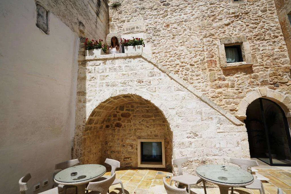 Cortile esterno in pietra con tavoli, scala e affaccio fiorito