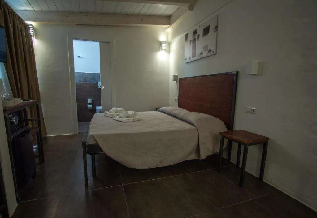 Camera con letto matrimoniale, testiera in legno e soffitto con travi