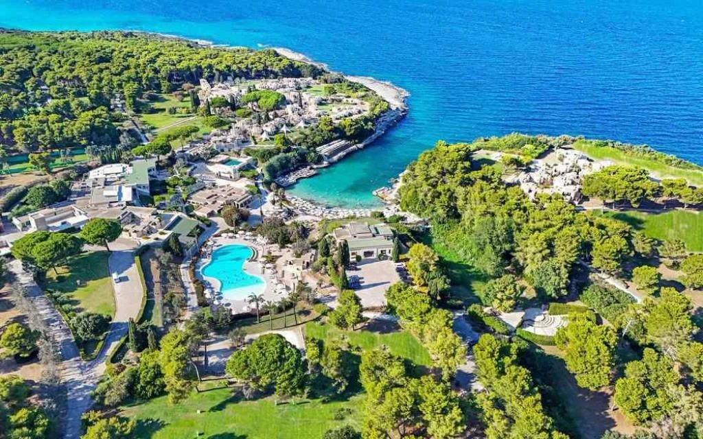 Veduta aerea del resort immerso nel verde con piscina e baia turchese