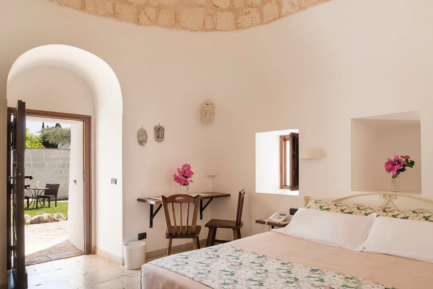 Camera in trullo con soffitto in pietra a cupola e arredi in legno