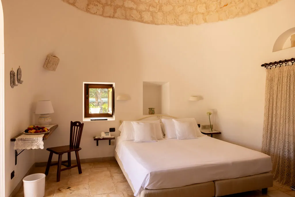 Camera in trullo con soffitto a cupola in pietra e letto matrimoniale