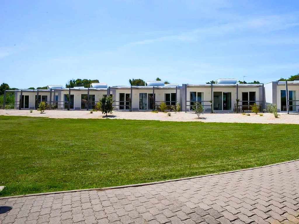 Fila di bungalow moderni con vetrate affacciati sul prato verde