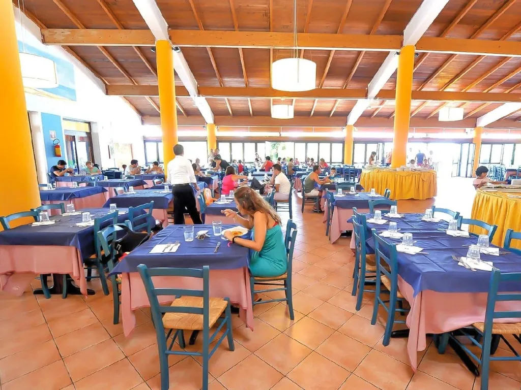 Sala ristorante interna con tavoli colorati e colonne gialle