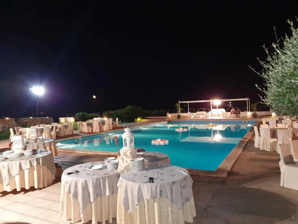 Piscina notturna con tavoli da buffet allestiti e luci decorative