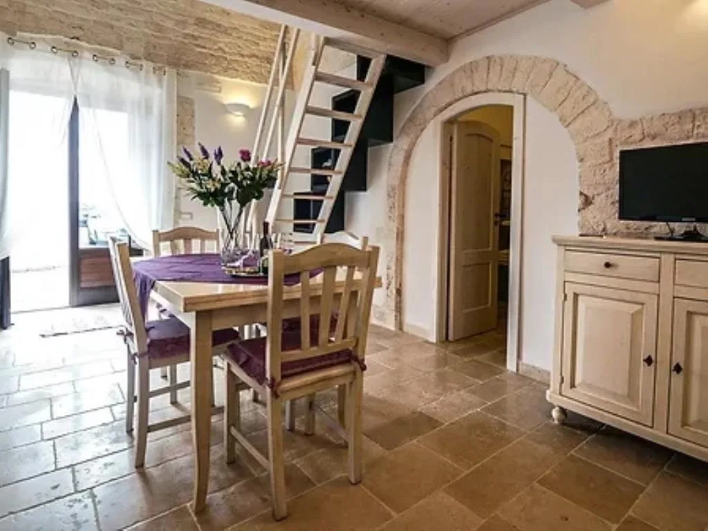 Soggiorno in stile rustico con arco in pietra, soppalco e tavolo da pranzo