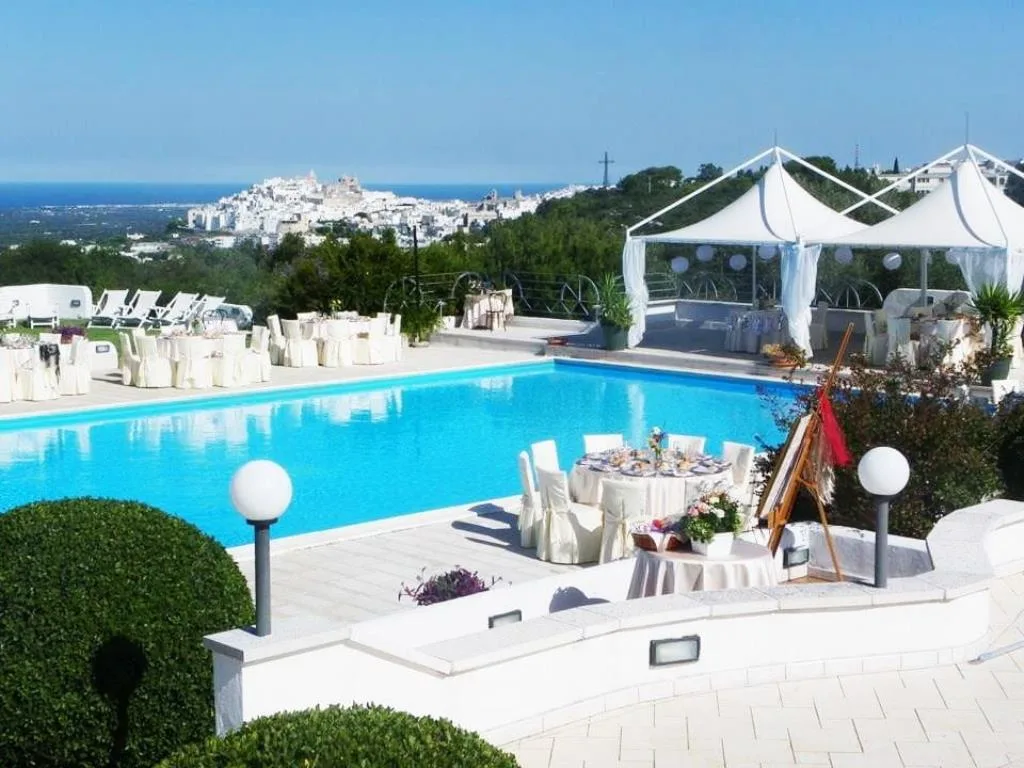 Piscina panoramica con vista sulla città bianca e gazebo allestiti per ricevimento