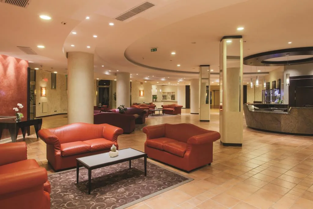 Hall dell'hotel con divani in pelle arancione, colonne e reception