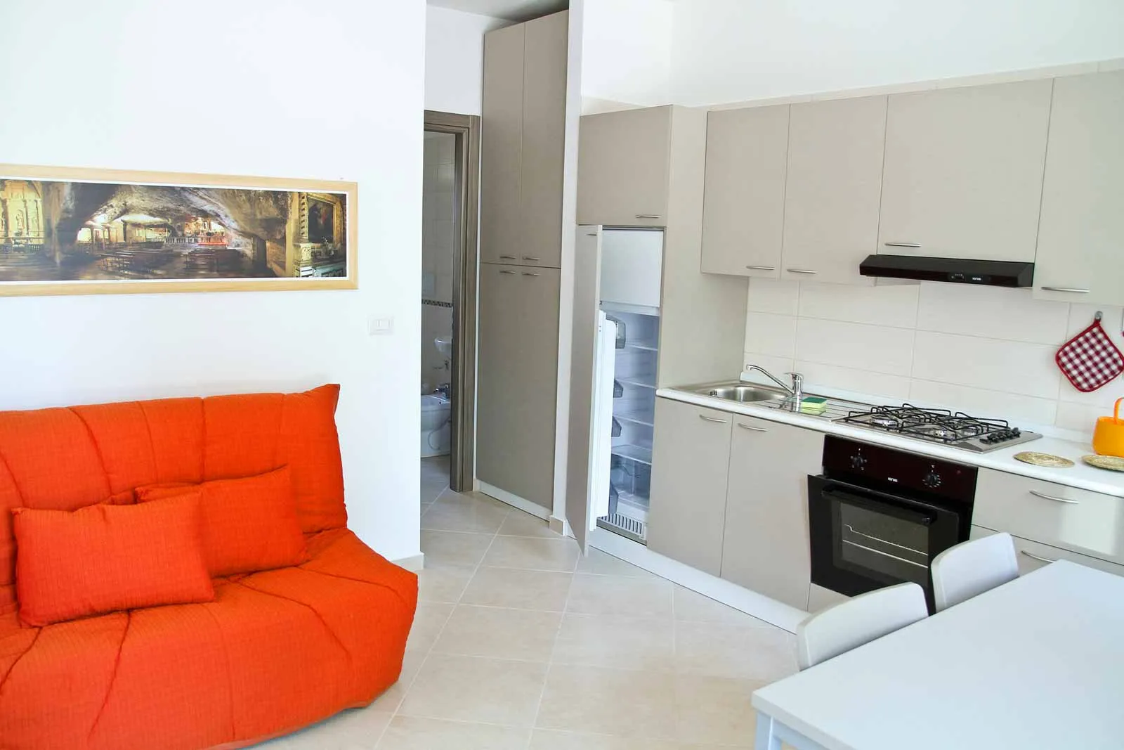 Interno di appartamento con cucina attrezzata e divano arancione