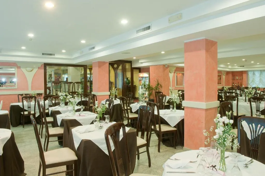 Sala da pranzo con colonne color terracotta, tavoli apparecchiati e composizioni floreali bianche
