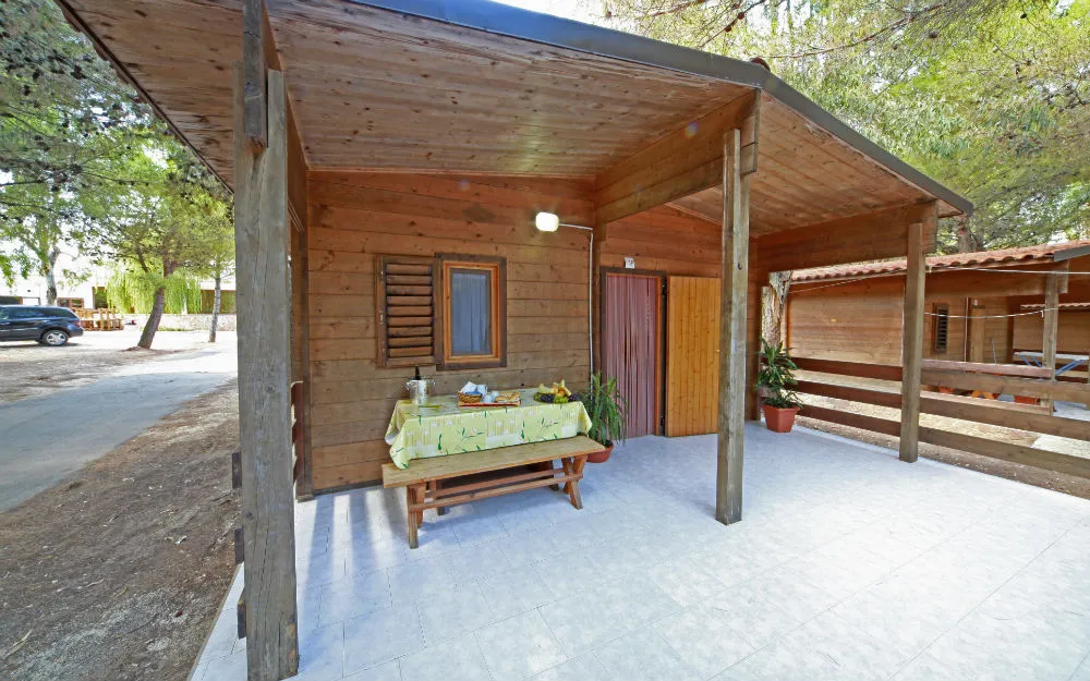 Veranda coperta in legno con tavolo da pranzo all'aperto davanti al bungalow