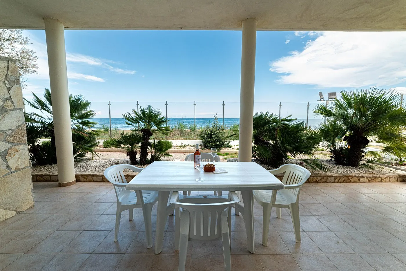 Veranda fronte mare con tavolo apparecchiato e vista panoramica sulla spiaggia