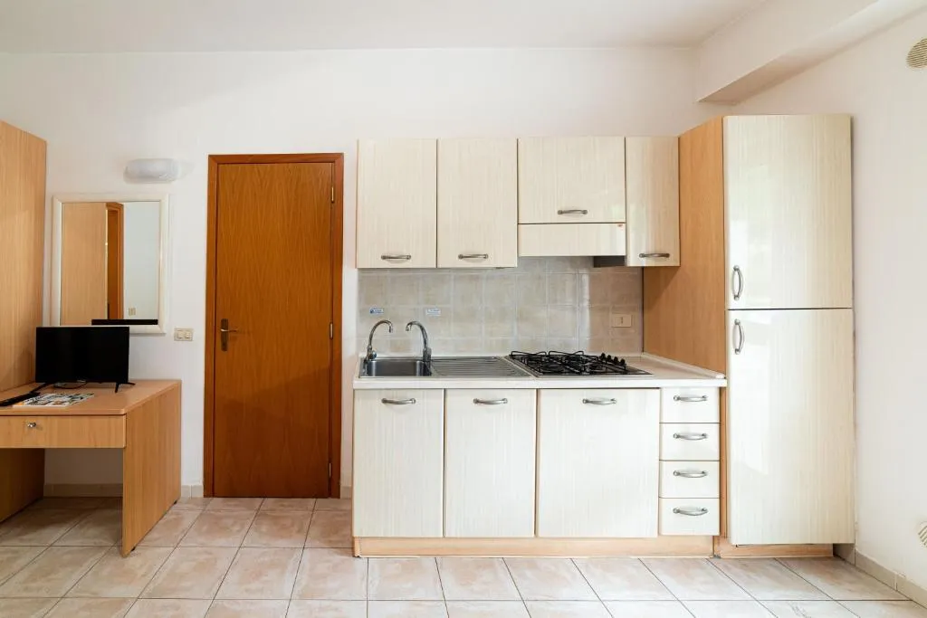 Monolocale con angolo cottura beige, scrivania e TV