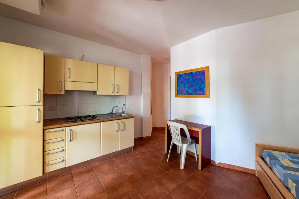 Monolocale con angolo cottura giallo, scrivania e letto singolo