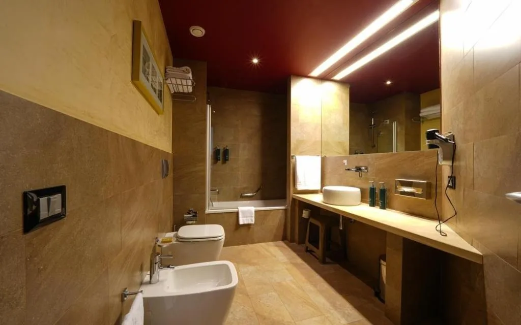 Bagno moderno in marmo beige con vasca, doppio lavabo, WC e bidet