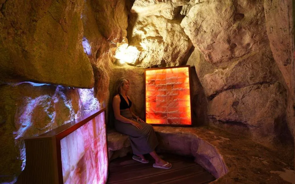 Grotta di sale con pareti rocciose e pannelli luminosi arancioni, donna seduta in relax