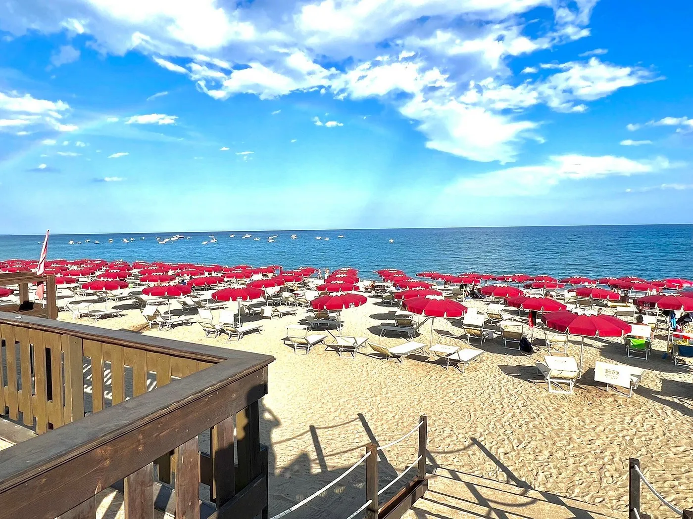 Spiaggia con ombrelloni rossi e lettini affacciata sul mare blu