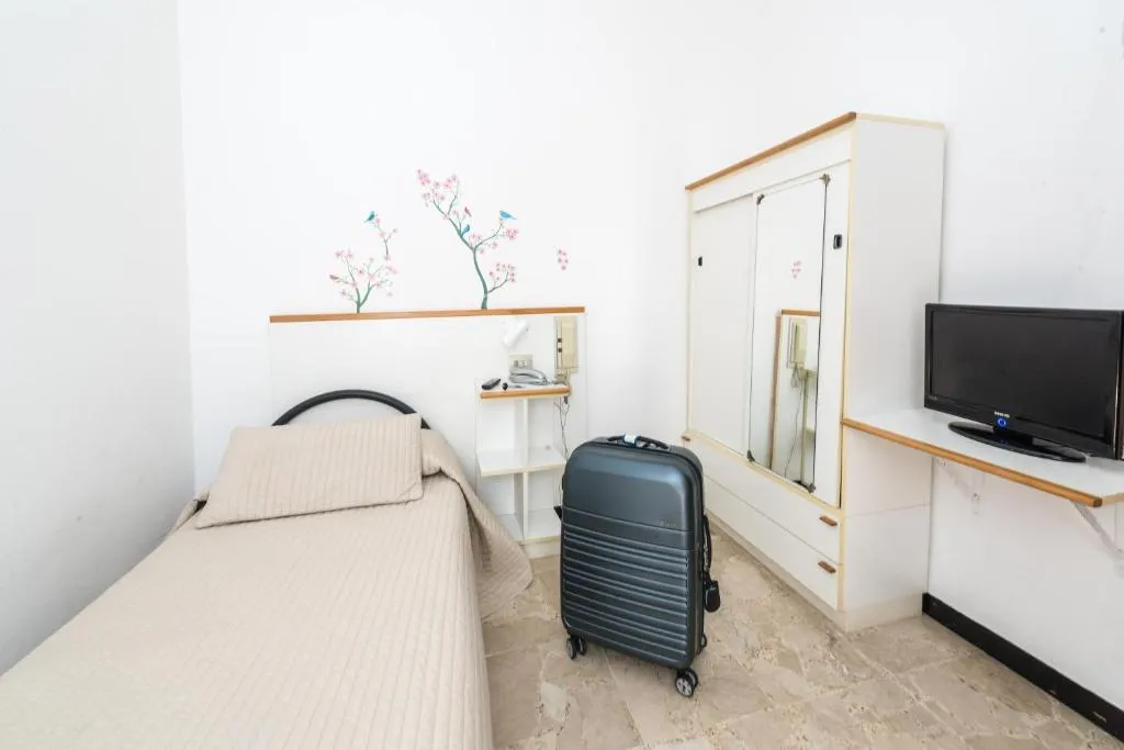 Camera singola con letto, TV e armadio bianco
