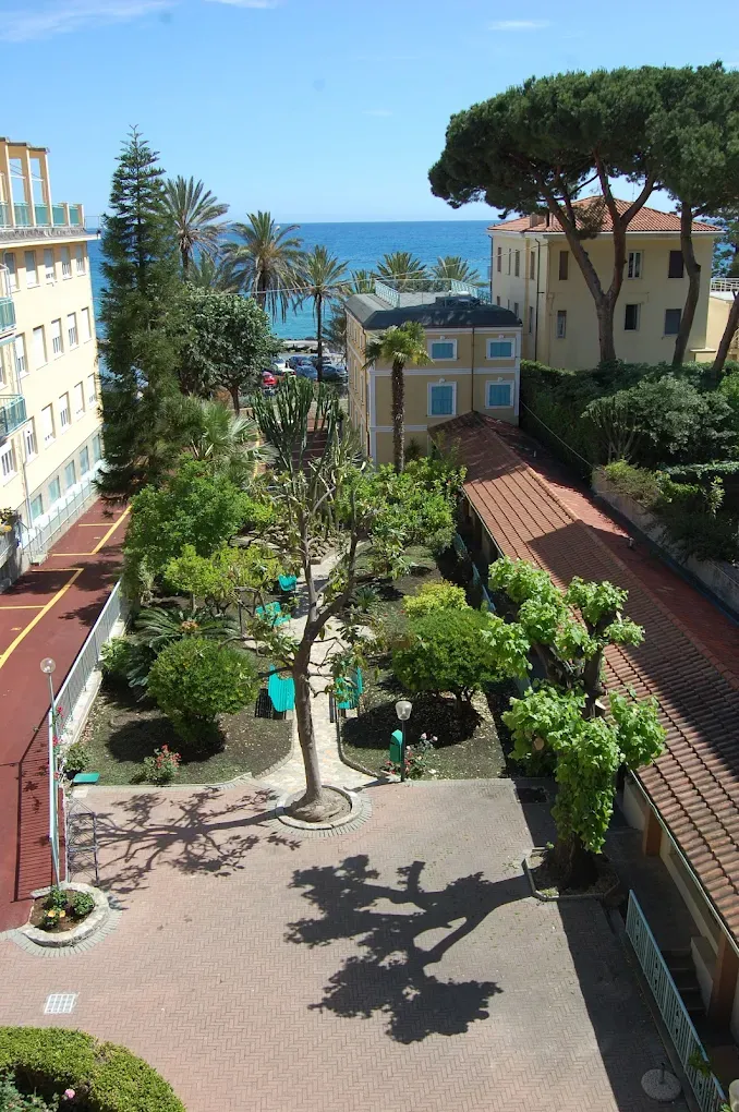 Vista panoramica del giardino dell'hotel con palme e mare azzurro sullo sfondo