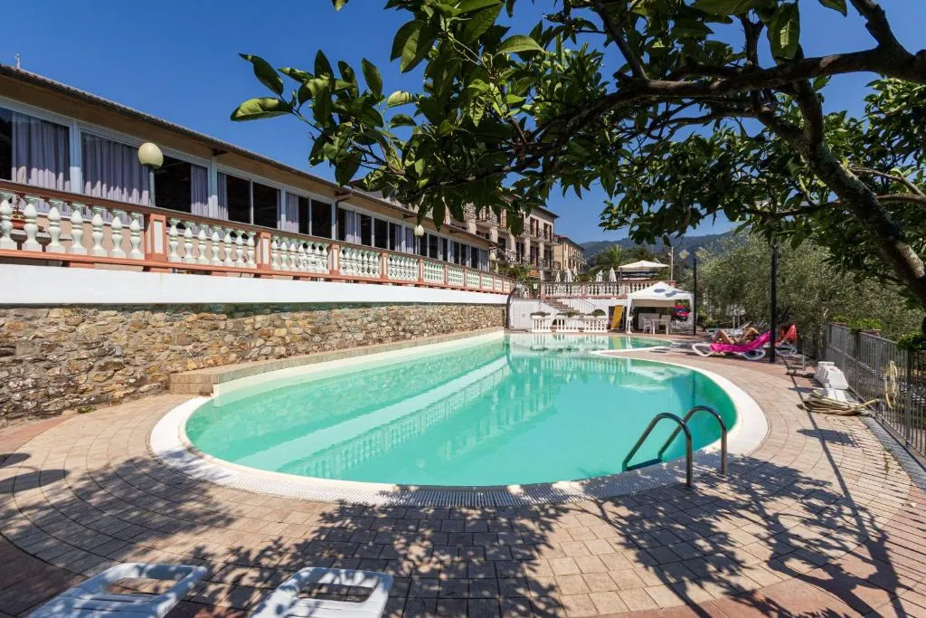 Piscina esterna con pavimentazione e lettini accanto all'edificio dell'hotel