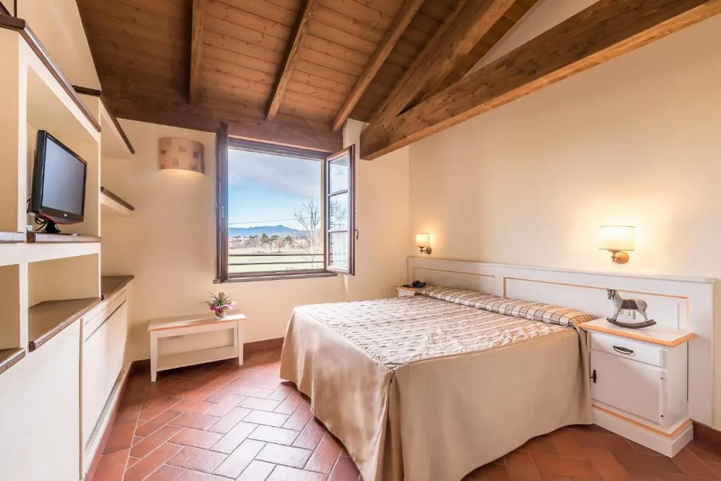 Camera matrimoniale con soffitto in legno, pavimento in cotto e vista sulle colline