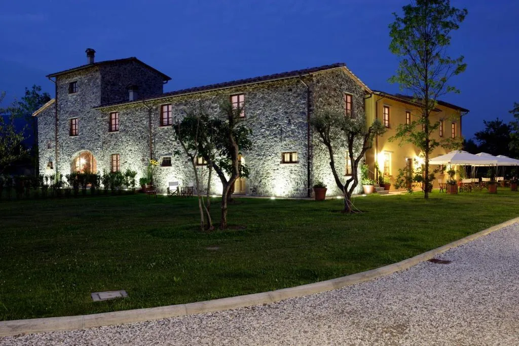 Casale in pietra illuminato di notte con giardino e ulivi