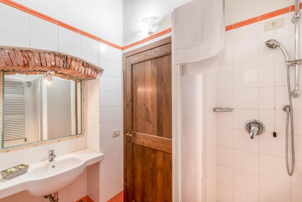 Bagno classico con lavabo, doccia e dettagli in cotto e legno
