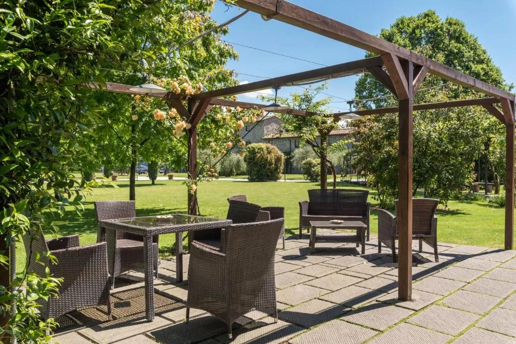 Area relax esterna con poltrone in vimini sotto pergolato e giardino