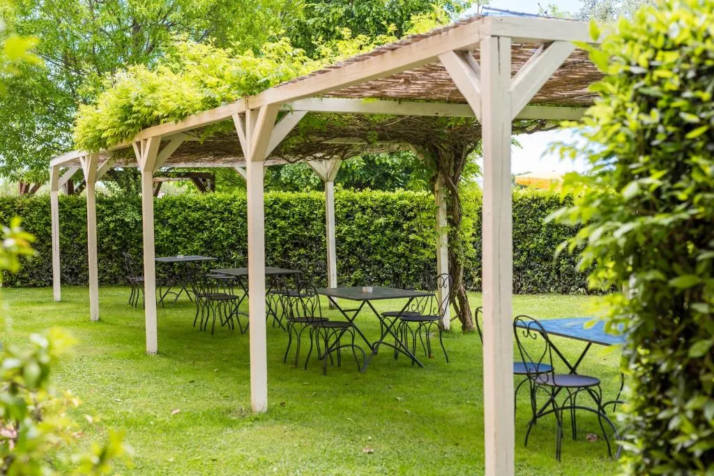 Pergolato in legno con tavoli e sedie in ferro battuto nel giardino
