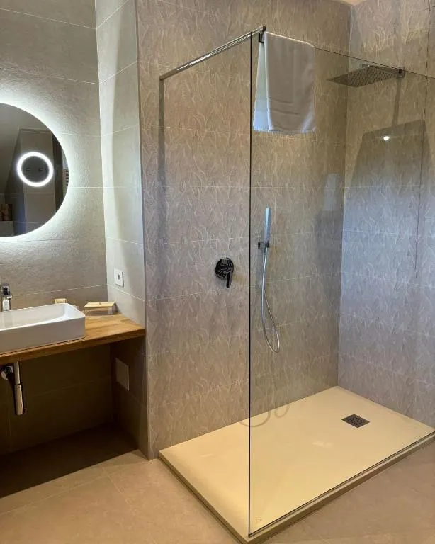 Bagno moderno con doccia walk-in in vetro e specchio rotondo retroilluminato