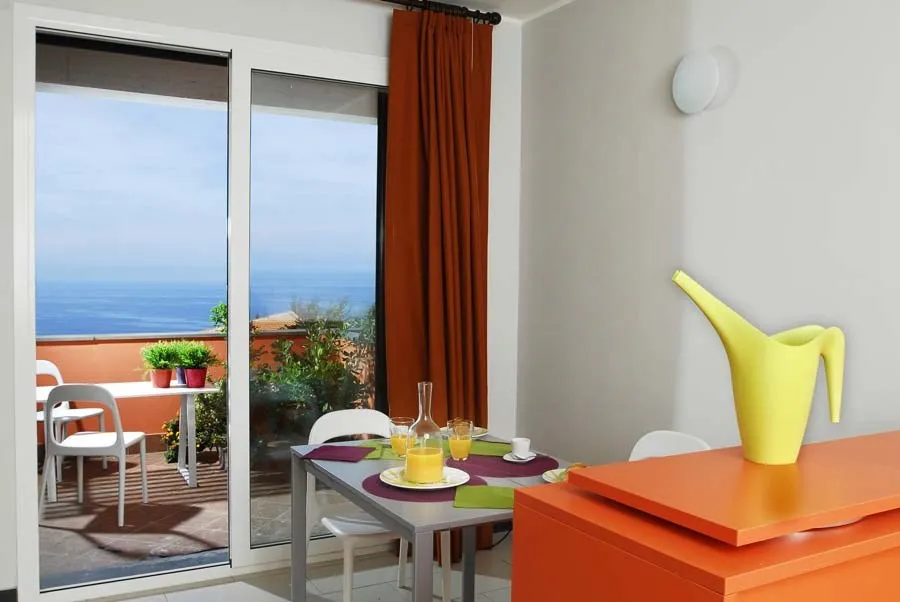 Zona pranzo e cucina con mobile arancione e terrazza con vista mare