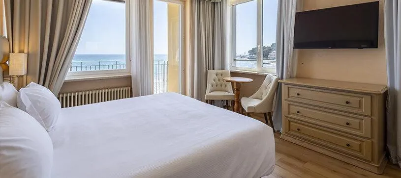 Camera con letto matrimoniale, TV a parete e finestre con vista sul mare