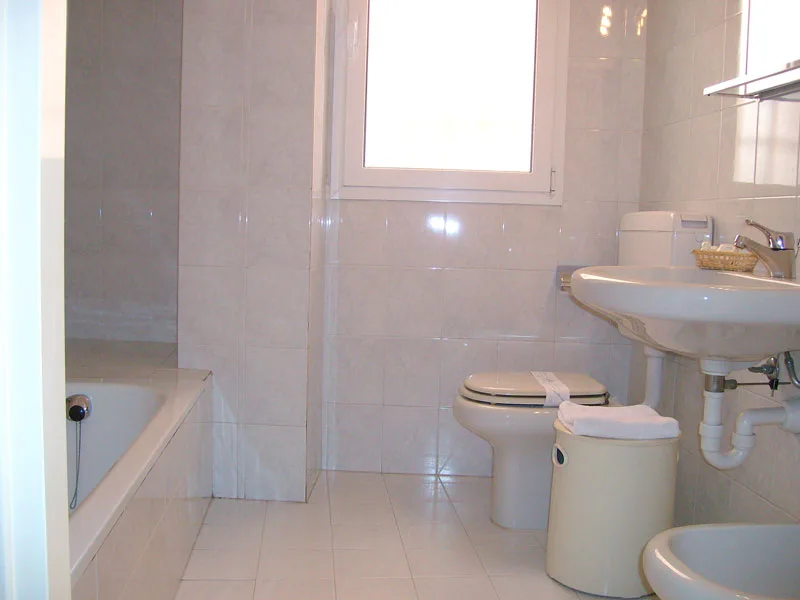 Bagno piastrellato chiaro con vasca, wc, bidet e lavabo