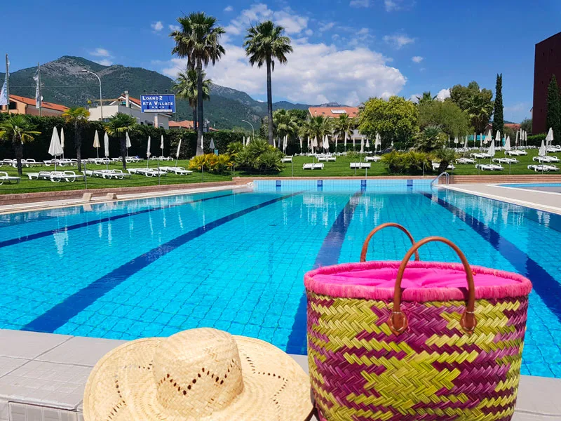 Piscina con cappello di paglia e borsa colorata a bordo vasca
