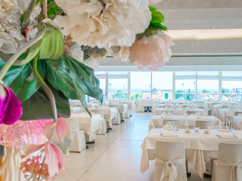 Sala ristorante elegante con tavoli apparecchiati e decorazioni floreali