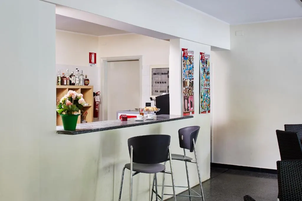 Bar interno con bancone, sgabelli e bottiglie sullo sfondo