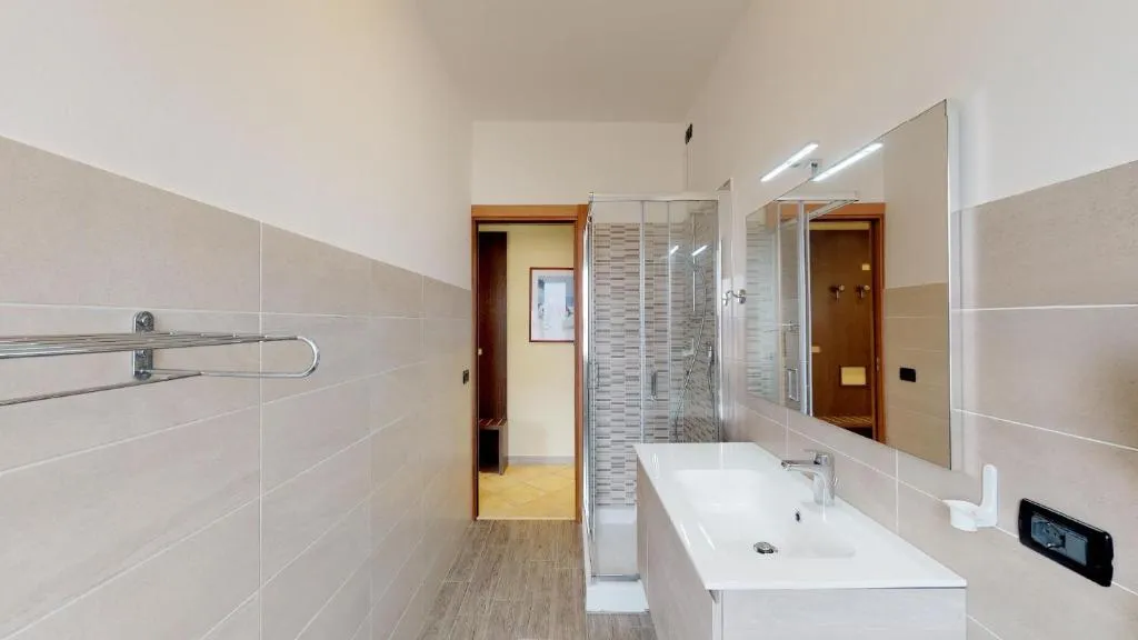 Bagno moderno con lavabo bianco, doccia e piastrelle beige