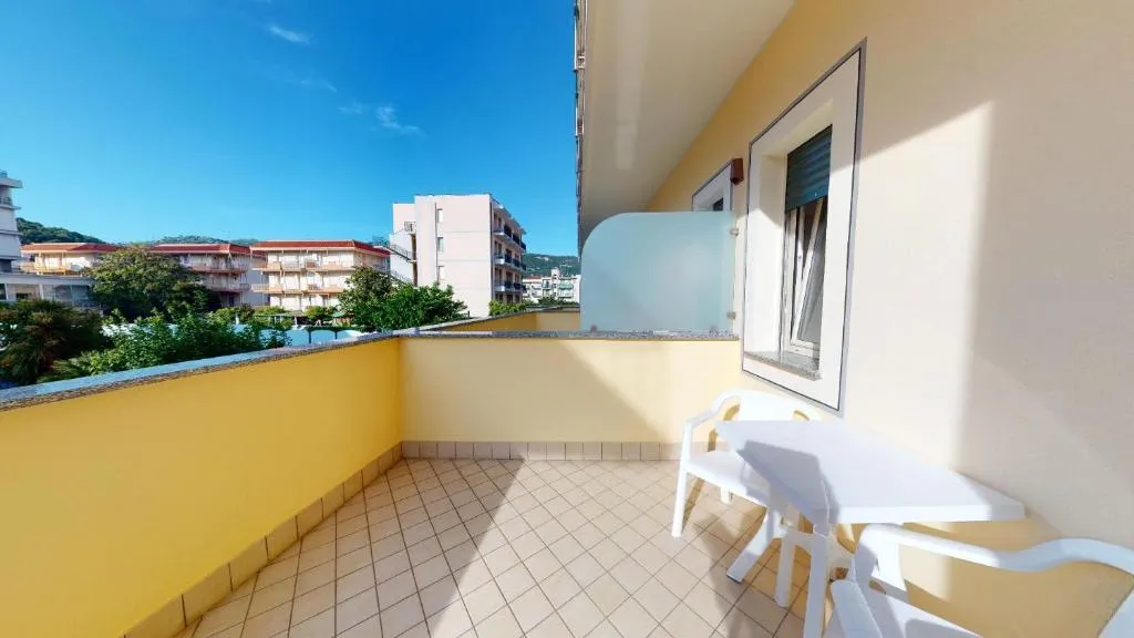 Balcone giallo con tavolino e sedia bianca con vista sul quartiere
