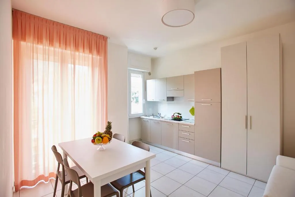 Cucina abitabile con tavolo da pranzo, frutta e tende rosa